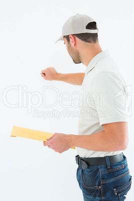 Delivery man with envelop knocking on white background