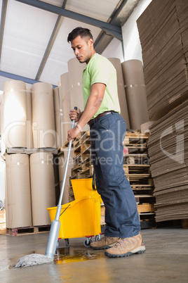 Focused man moping warehouse floor