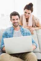 Smiling coworkers using laptop together