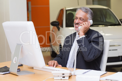 Smiling businessman using laptop on the phone