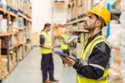 Focused warehouse manager writing on clipboard