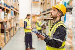 Focused warehouse manager writing on clipboard