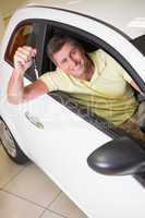 Smiling man holding a car key sitting in his car