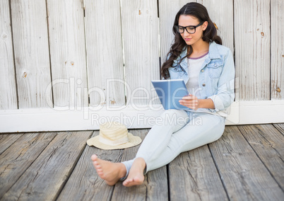 Pretty hipster sitting on ground with tablet