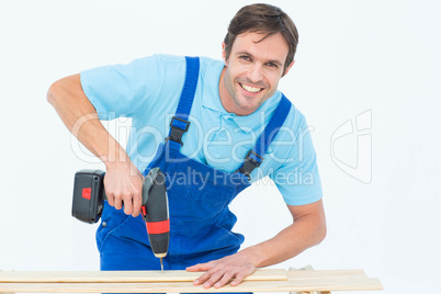 Carpenter using drill machine on wood