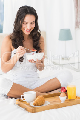 Happy brunette having breakfast in bed