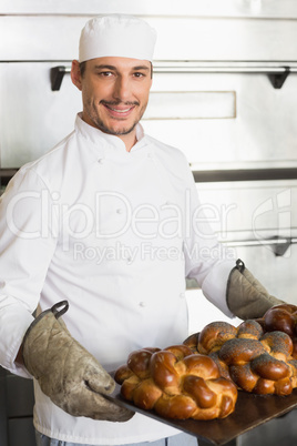 Happy baker showing tray of fresh bread