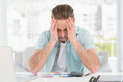 Stressed businessman covering his face at his desk