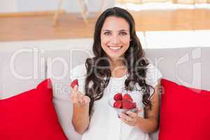 Pretty brunette eating strawberries on couch