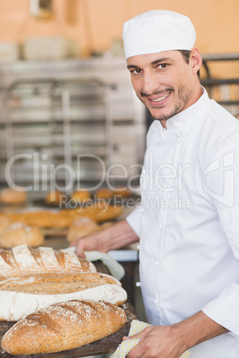 Smiling baker holding tray of bread