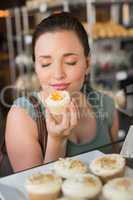 Pretty brunette smelling a cupcake