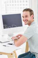 Smiling businessman sitting at desk typing on keyboard