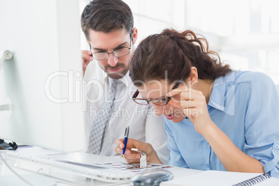 Focused coworkers looking photos together