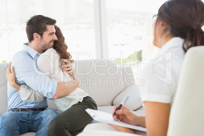 Smiling couple hugging in front of their therapist