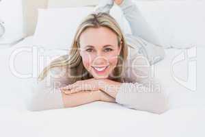 Smiling blonde lying on the bed looking at camera
