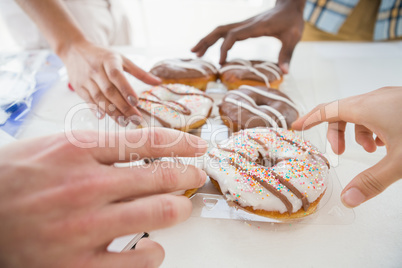 Hands of business people taking doughnut