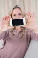 Pretty blonde showing screen of smartphone