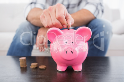 A man putting coins in piggy bank