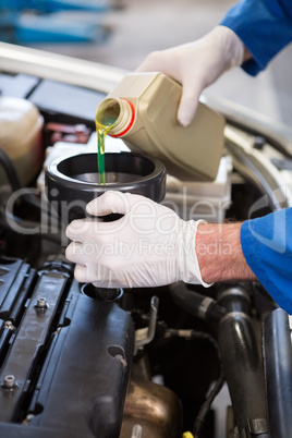 Mechanic pouring oil into car