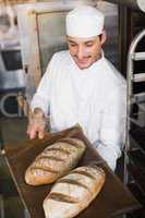 Happy baker holding tray of fresh bread