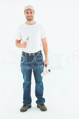 Happy man holding paint roller and paintbrush