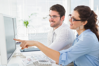 Smiling business coworkers pointing screen of computer