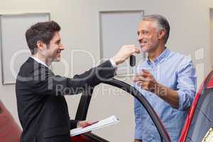 Businessman giving car key while shaking a customer hand