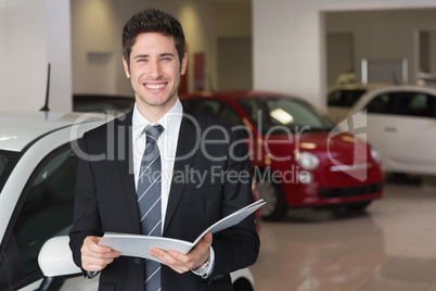 Businessman reading over a booklet smiling at camera