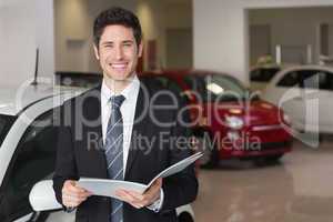 Businessman reading over a booklet smiling at camera