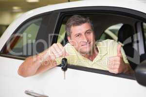 Positive customer holding a key sitting in his car