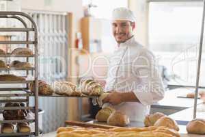 Smiling baker holding tray of bread
