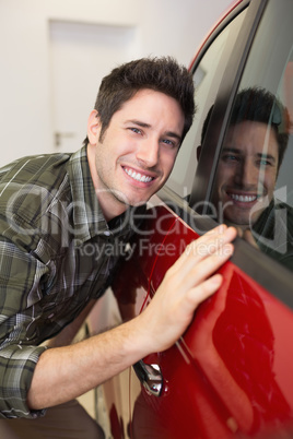 Smiling man hugging a red car