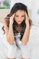 Worried brunette sitting on bed