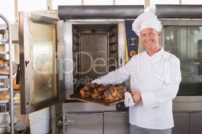 Happy baker taking out fresh bread