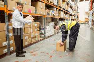 Manager watching worker carrying boxes