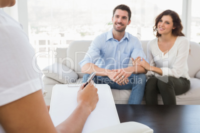 Reconciled couple smiling and talking with their therapist