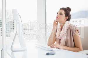 Pretty businesswoman typing on keyboard and thinking