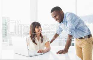Smiling coworkers using laptop together