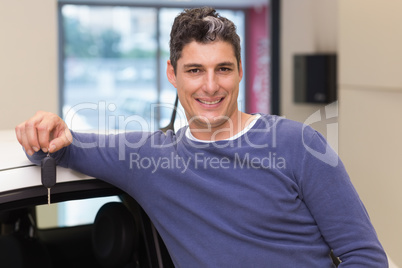 Smiling customer leaning on car while holding his key