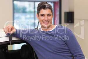 Smiling customer leaning on car while holding his key