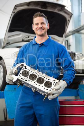 Smiling mechanic holding an engine Smiling mechanic holding an engine