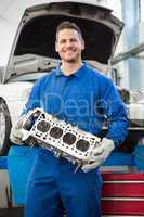 Smiling mechanic holding an engine