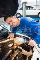 Mechanic examining under hood of car with torch