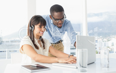 Smiling coworkers using laptop and headset Smiling coworkers using laptop and headset