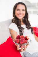 Pretty brunette eating strawberries on couch