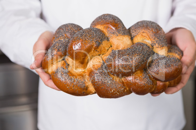 Baker showing freshly baked loaf