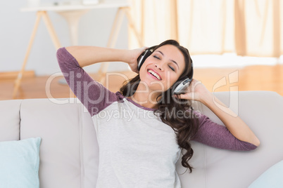 Pretty brunette listening to music on the couch