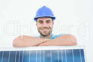 Happy construction worker leaning on solar panel