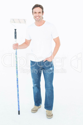 Confident man holding paint roller on white background