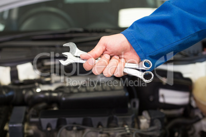 Mechanic holding pair of wrenches